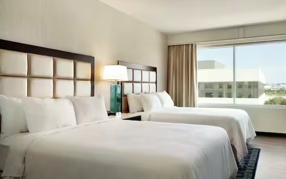 Two hotel beds with large window at The Embassy Suites By Hilton Landmark Hotel