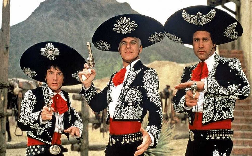Actors Martin Short, Steve Martin, and Chevy Chase dressed in decorative black and red cowboy clothes while acting in Three Amigos