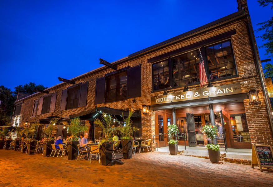 Nighttime street scene with storefronts and outdoor seating.
