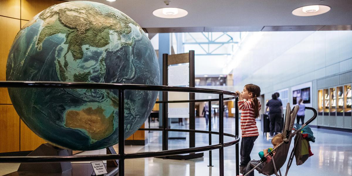 Girl staring at the giant globe in the concourse of the Allen County Public Library
