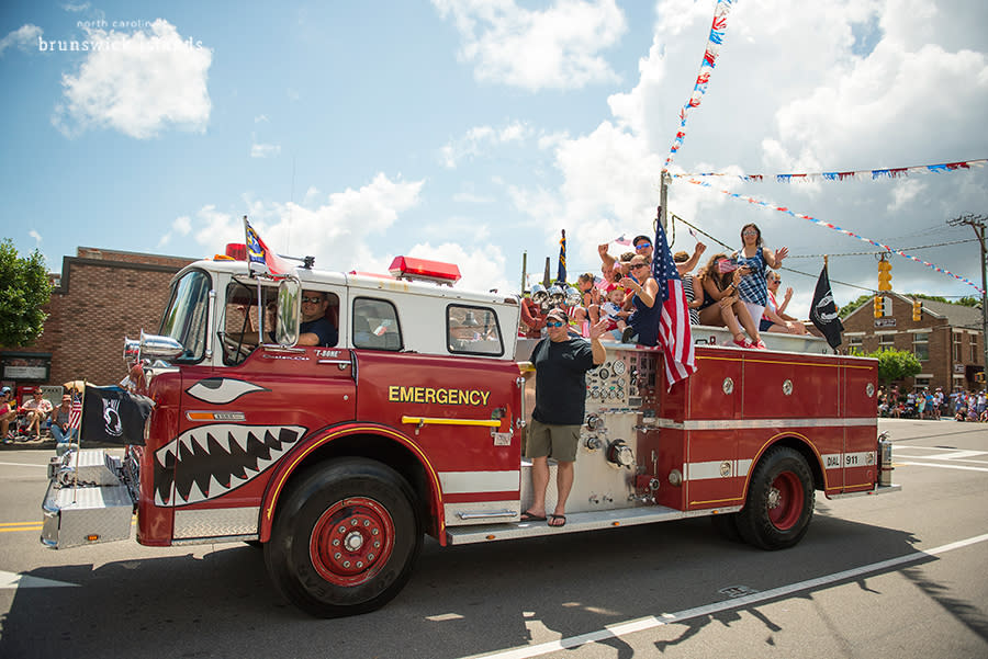 a firetruck carrying passengers in a street parade at the NC 4th of July Festival in downtown Southport