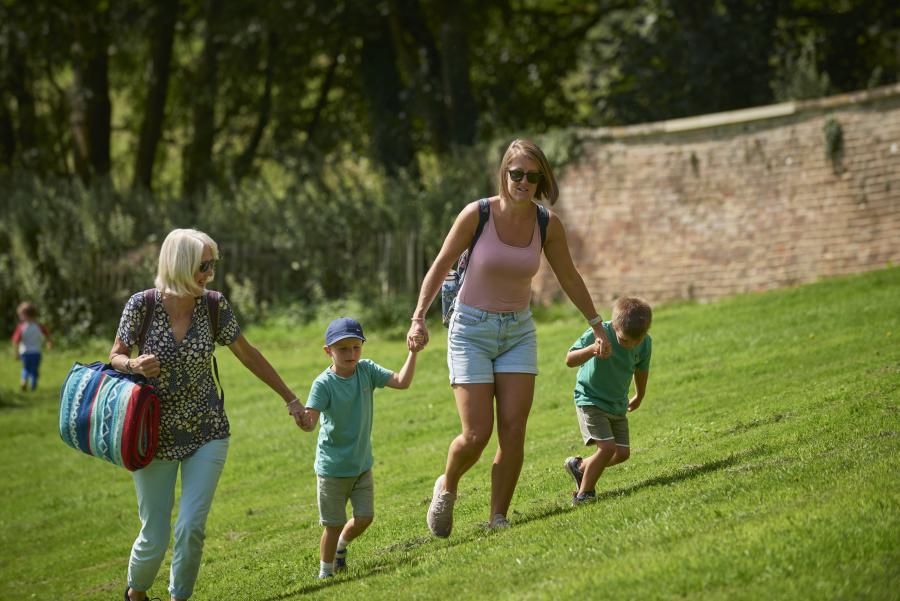 A grandmother, mother and two children walking to find a picnic spot at Newark Park