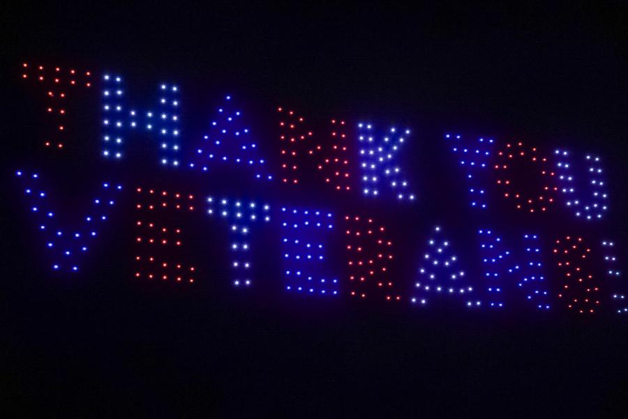 "Thank you Veterans" spelled out in the sky in red, white, and blue with drones.