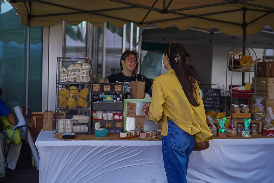 A woman talking to a vendor at a farmers market