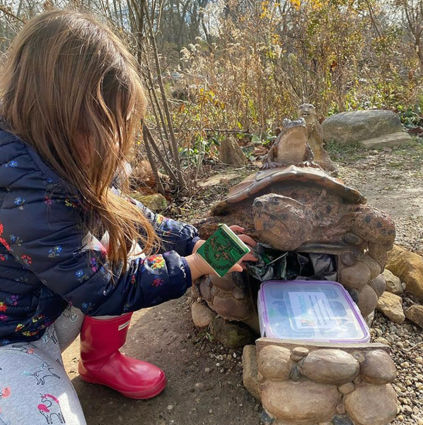 Little girl discovering a Riverbox shaped like a turtle and stamping her passport