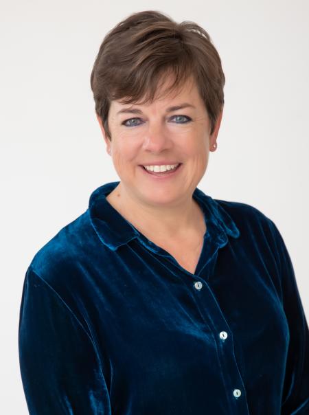 A caucasian woman with short hair smiles at the camer