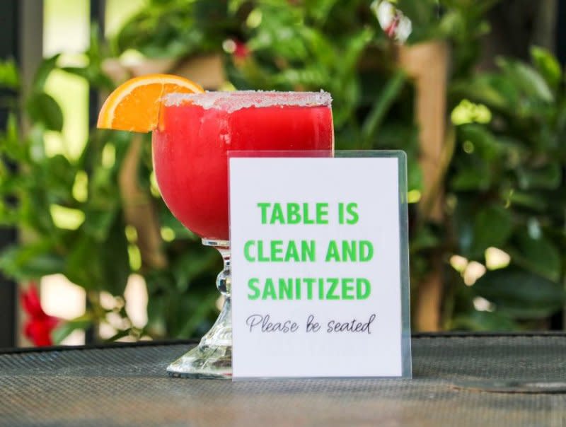 A sugar-rimmed glass with a red drink and an orange slice sits on an outside table at Teresa's Mexican Restuarant