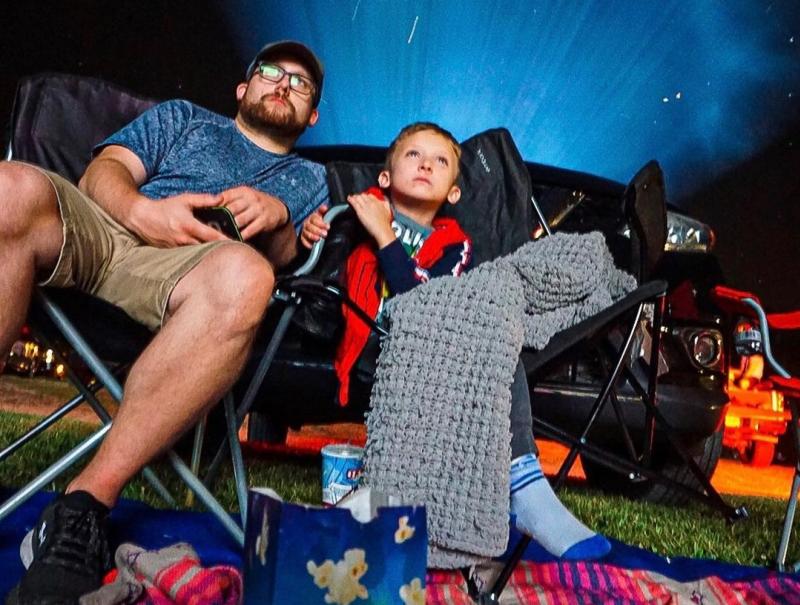 A father and son watching a movie at the Starlite Drive-In