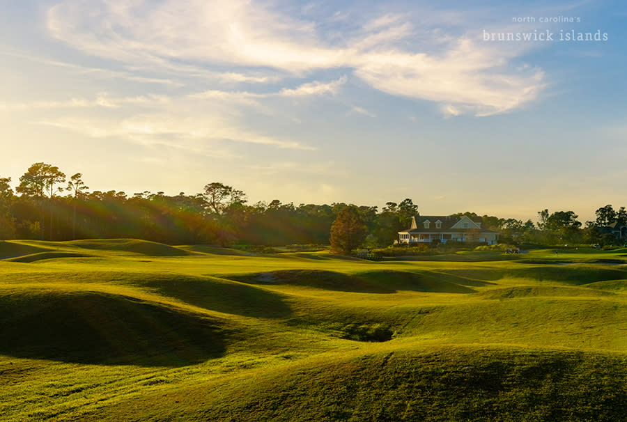 a view of a rolling golf course and a clubhouse in the distance