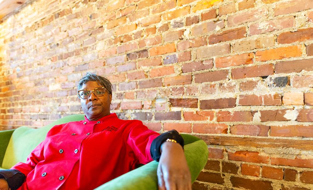 Serving Spoon Owner sits in her restuarant and event center with a chef's coat on