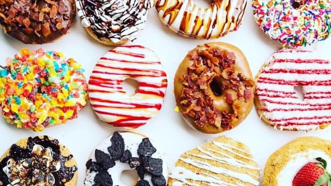A dozen donuts with different glazes and toppings viewed from above.