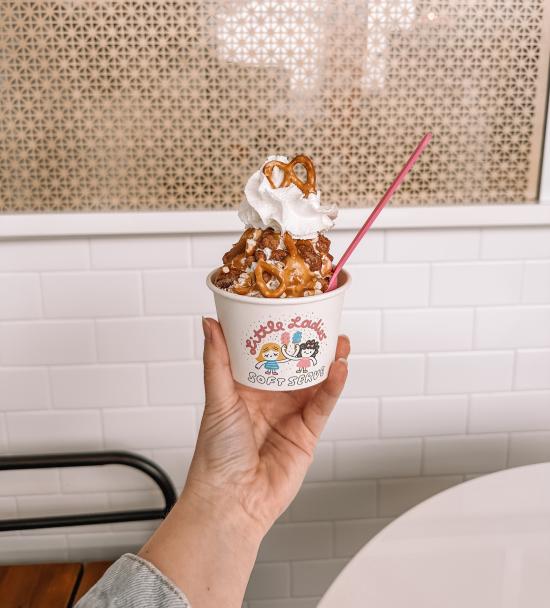 A hand holding up an ice cream sundae at Little Ladies Soft Serve