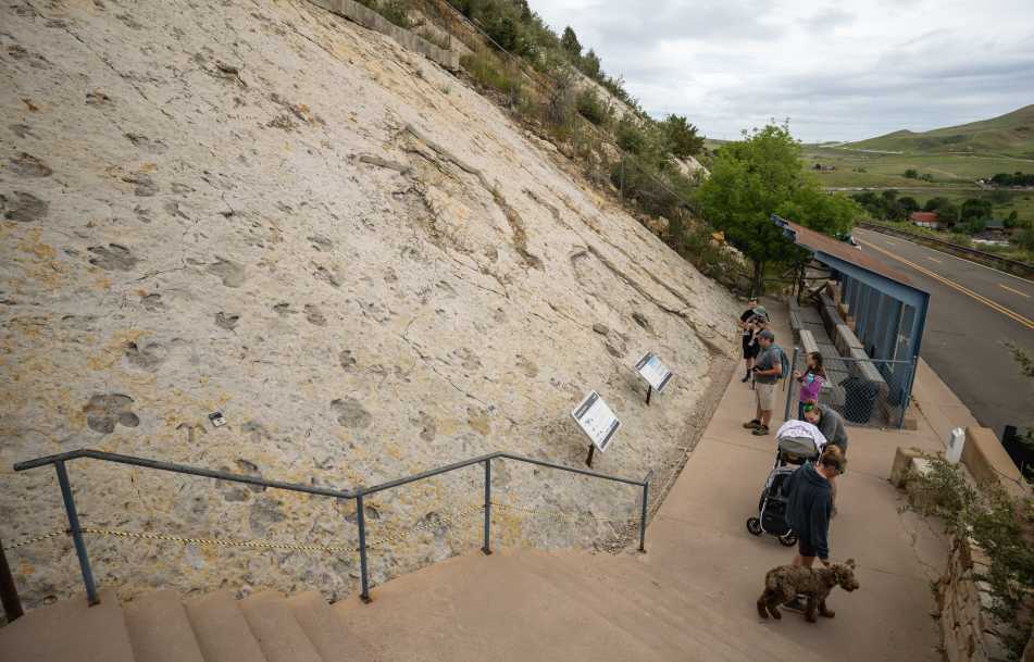 Several visitors and a dog are climbing the steps at Dinosaur Ridge in Denver, Colorado.