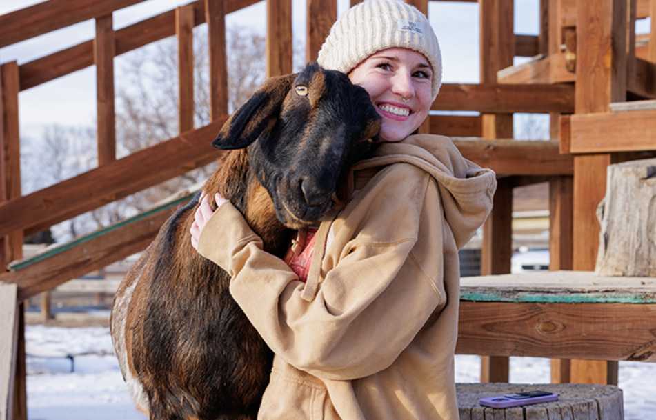 A woman hugging a goat at Luvin Arms Animal Sanctuary in Erie, Colorado