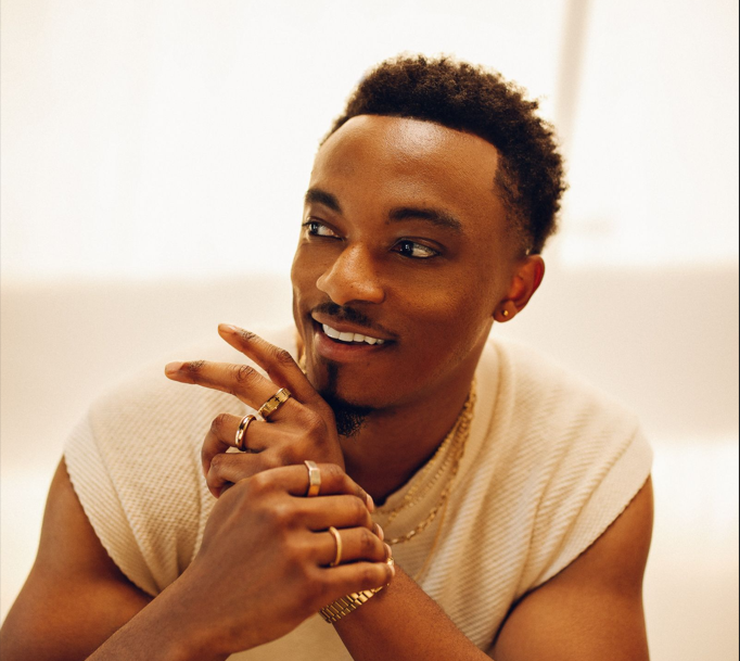 Jonathan McReynolds poses for a photo wearing a white T-shirt and several rings on his fingers