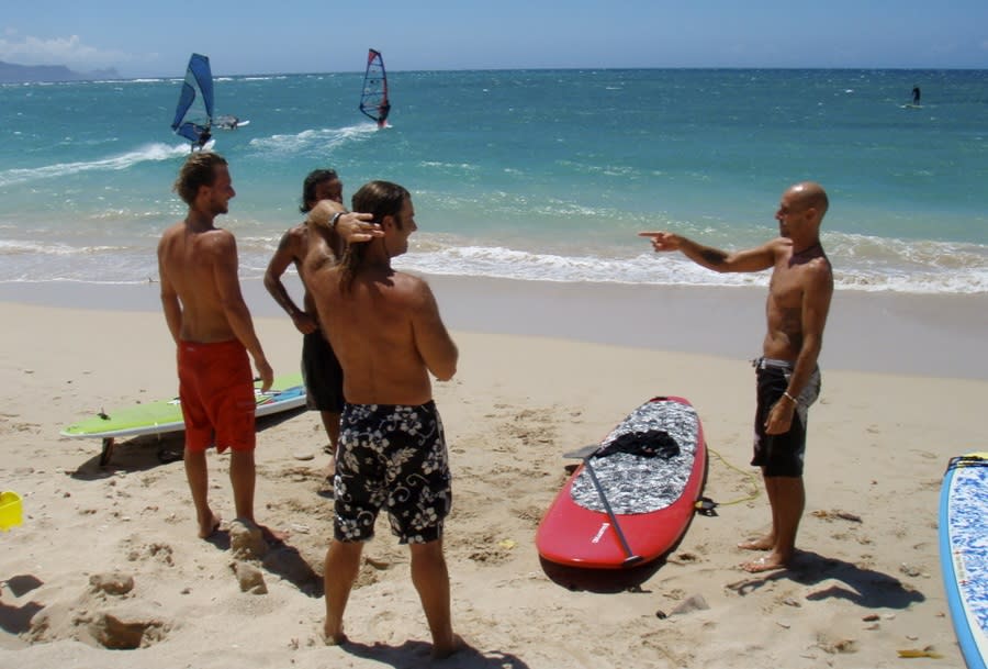 Four men getting ready to go out into the ocean with SUP boards and surf boards in Pompano Beach.