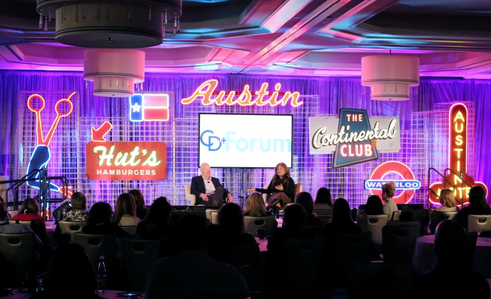 Meeting attendees watching a panel discussion on an Austin themed stage.