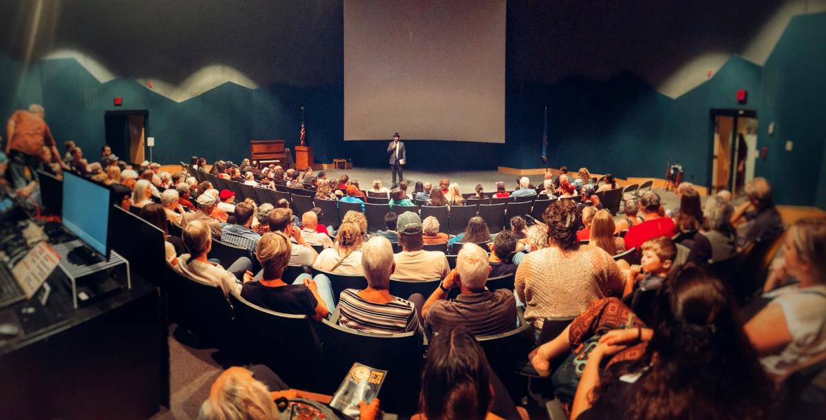 Audience members fill a theater during the Black Hills Film Festival as a speaker addresses the crowd from the stage.