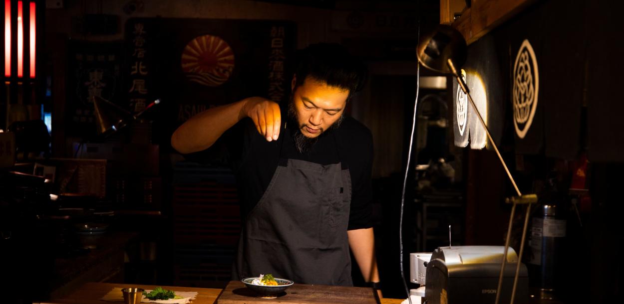 Chef Tatsu Aikawa sprinkles ingredients over a dish