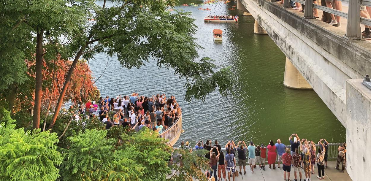 View from north side of Congress Avenue Bridge of crowd along gathering to watch the Austin bats.