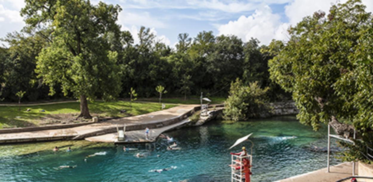 People swimming in Barton Springs Pool with lifeguard in stand