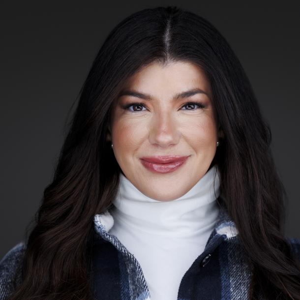 Photo of Monica Higgins from the shoulders up wearing a white turtleneck and blue plaid jacket