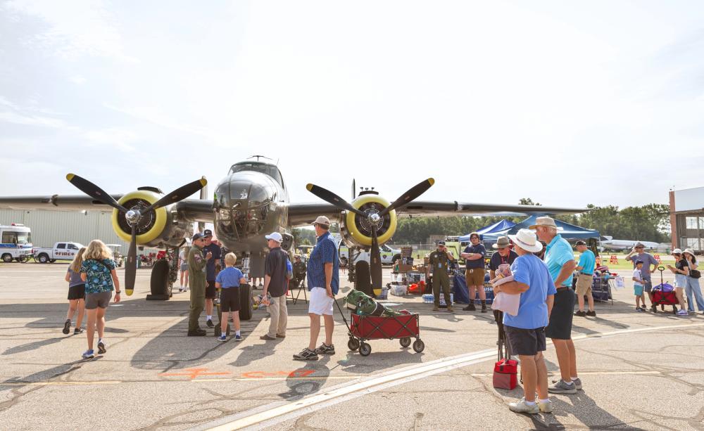 Historic plane parked in airport parking lot as visitors get up close to the exterior for a closer l…