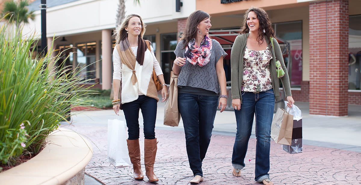 Three women dressed in fashionable fall clothes carry shopping bags as they walk around Tanger Outlets in Myrtle Beach