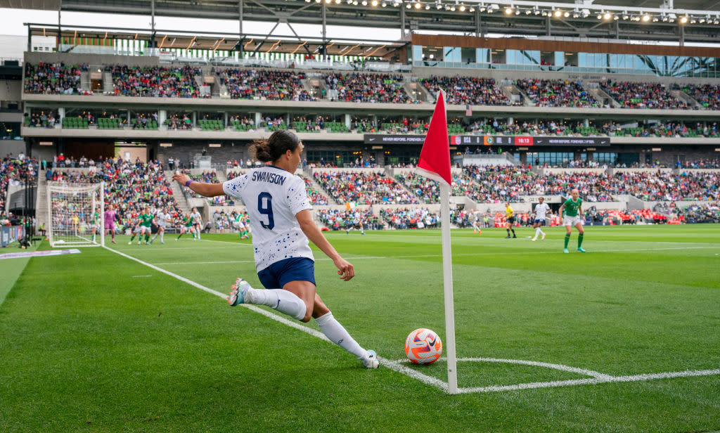 A player on the USWNT kicking the ball from the edge of the field towards her teammates.