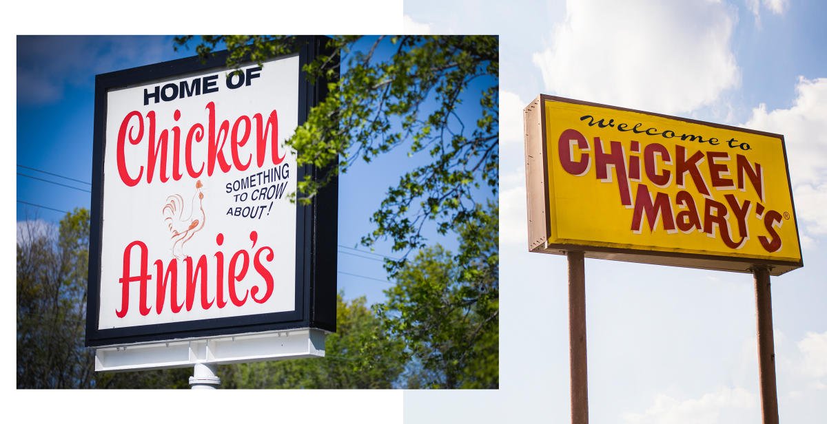 two restaurant signs side-by-side. One is white and says "Chicken Annie's" in red. The other is yellow and says "Chicken Mary's" in red.
