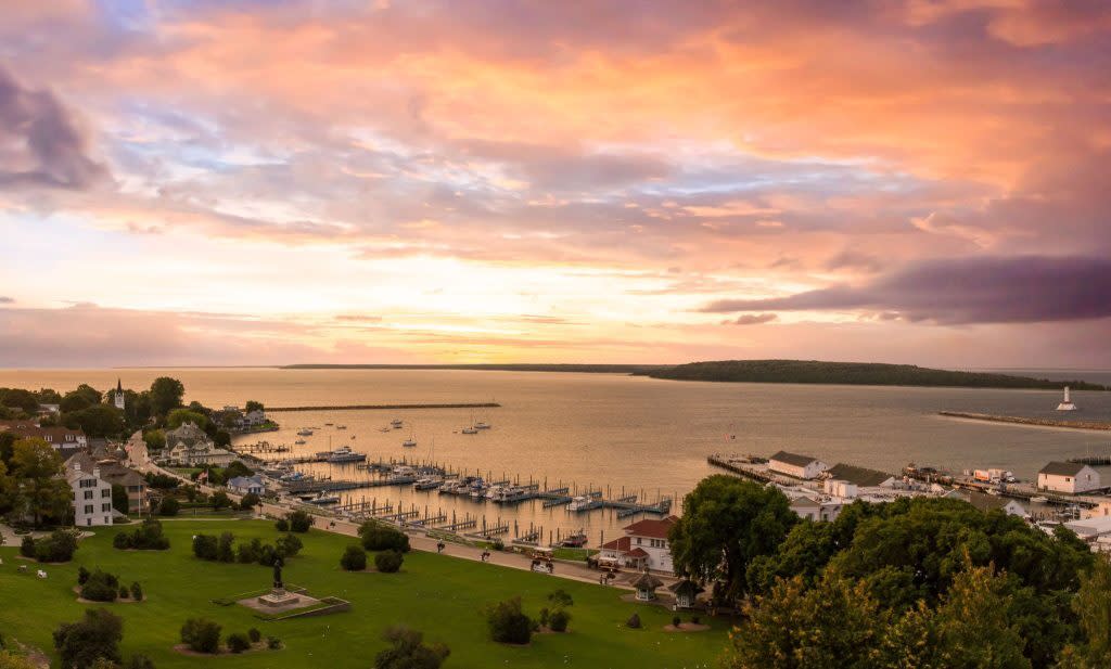The sun rises over the Mackinac Island harbor and marina full of boats
