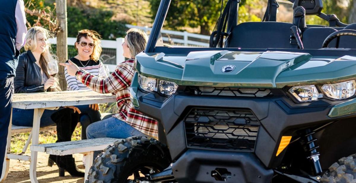 A group of friends sits next to an all terrain vehicle