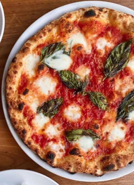 Aerial view of table with plate of pizza, pesto pasta and bread