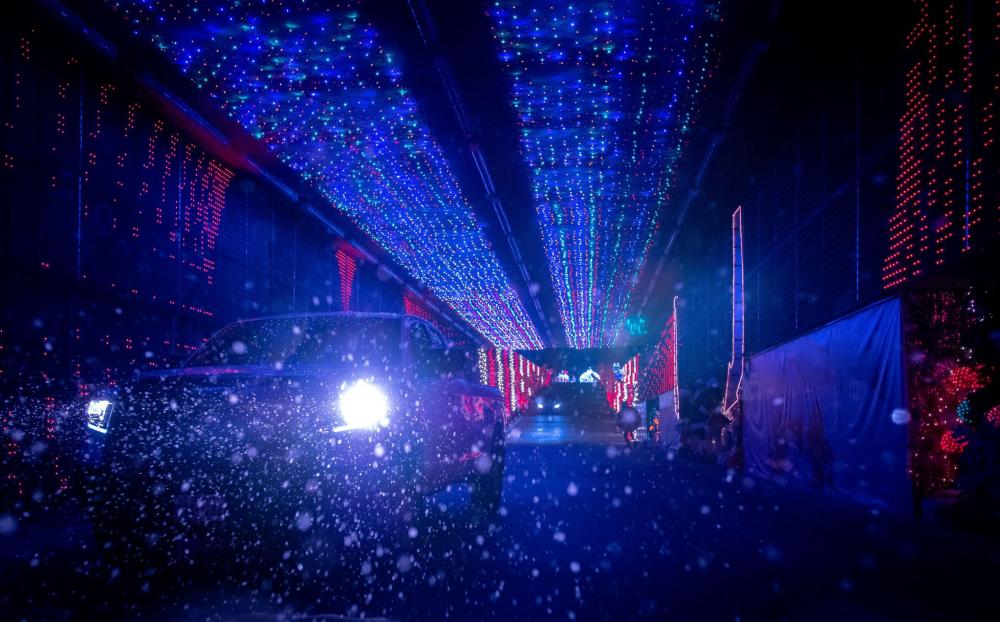 Car driving through snowy tunnel of lights at Peppermint Parkway