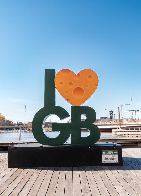 Sculpture that says I heart Green Bay and the heart looks like a piece of cheese. This sculpture is on the Fox River in Green Bay