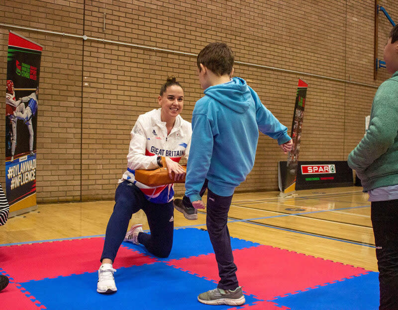 A child trying kick boxing with an Olympic athlete