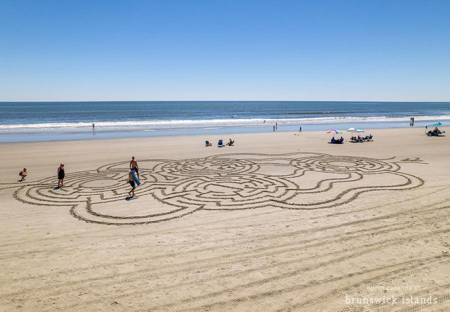 people navigating a maze drawn in the beach