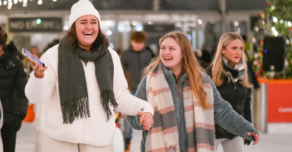 Two women holding hands ice skating laughing at Westquay On Ice
