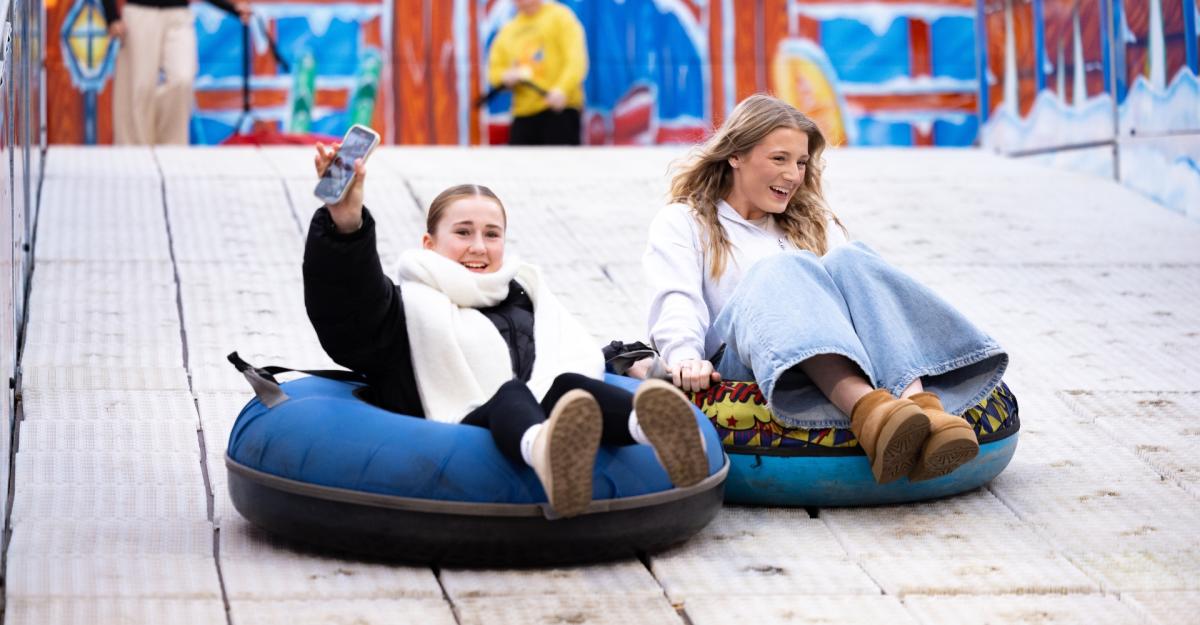 Two girls sliding down the big snow slide at the Christmas Market
