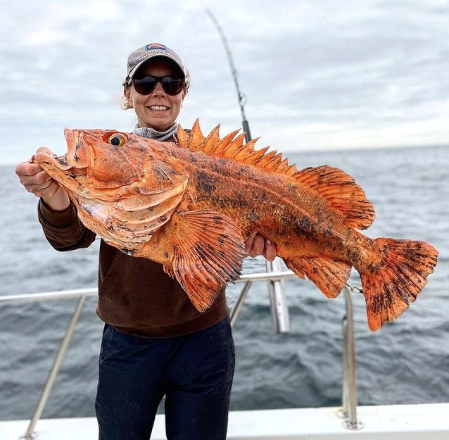 a woman on a fishing charter holds up a rockfish