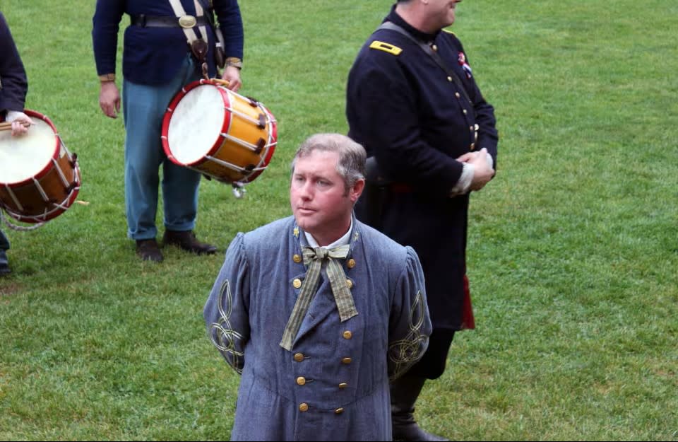 A historical interpreter dressed as a Confederate soldier stands outside Fort Mackinac on Mackinac Island