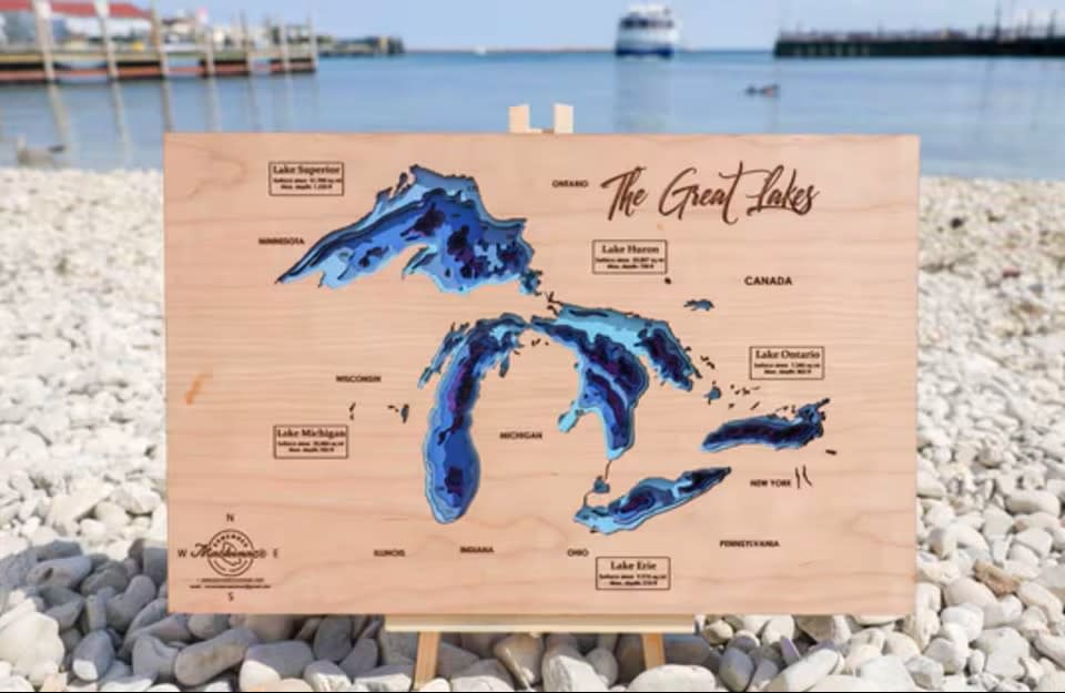 Laser-engraved wooden map of The Great Lakes standing in rocks along Mackinac Island shoreline