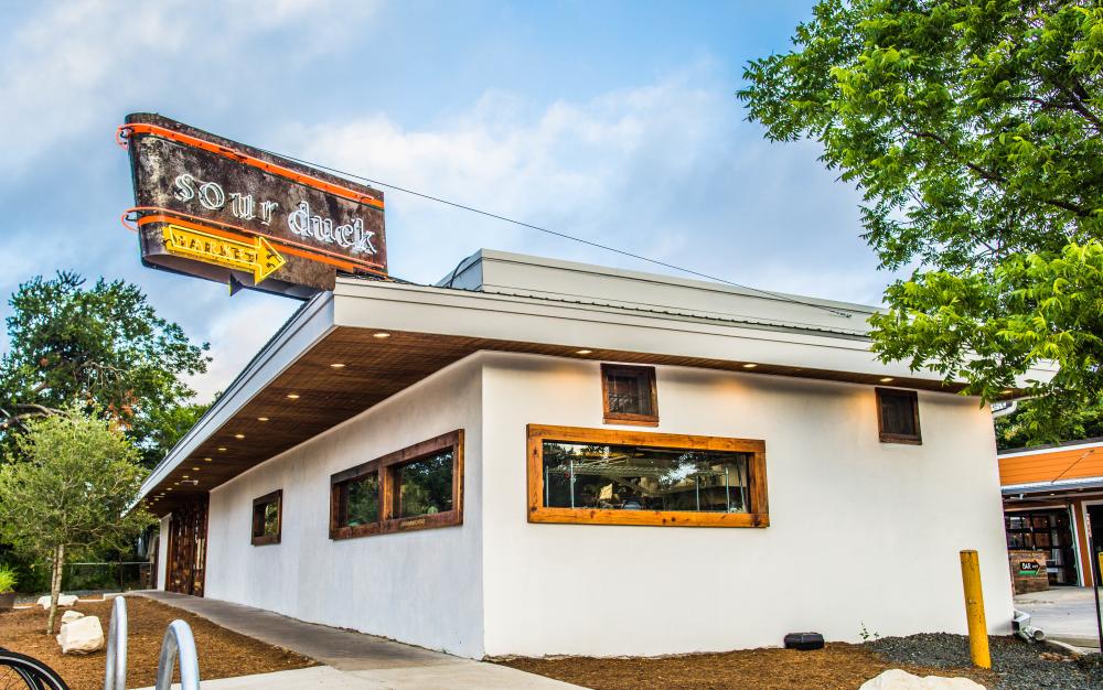 exterior of Sour Duck restaurant with rustic neon sign