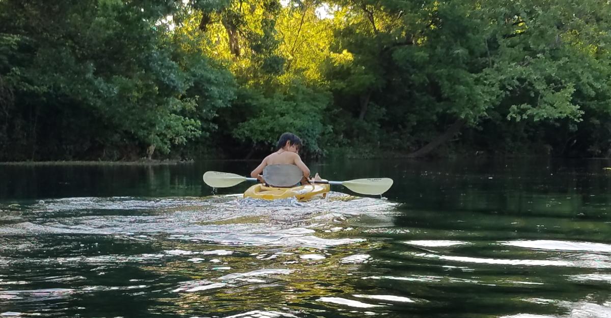 Boy alone in kayak on calm river