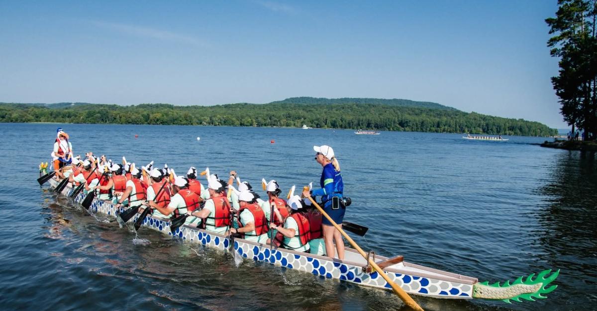 A team of 20 rowers, a drummer and a steerer race a 46-foot-long traditional dragon boat across the water.