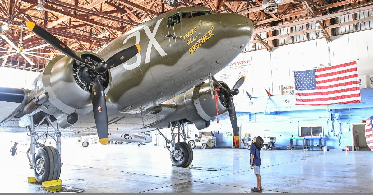 A boy looks up at a restored WWII-era Douglas C-47 Skytrain on display in San Marcos, TX