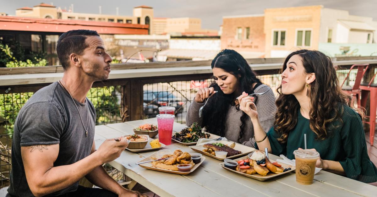 Three people enjoying meal on rooftop deck downtown