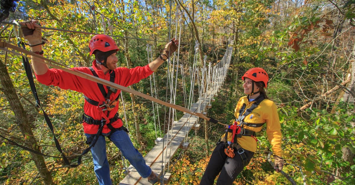 Two people on zipline at Boone Creek Outdoors in the fall.