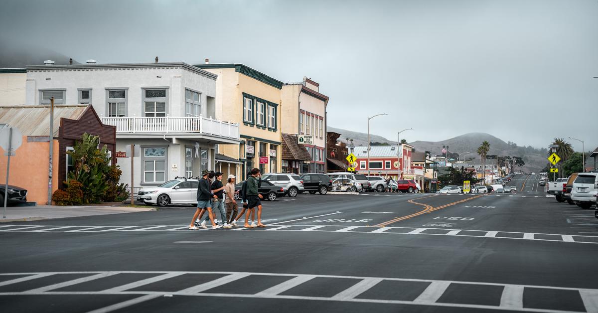 group of people crossing the street in front of shops in Cayucos