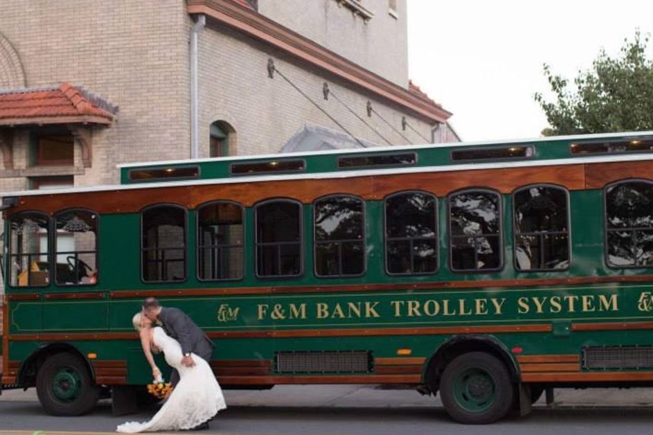 Bride and groom kissing beside a green trolley